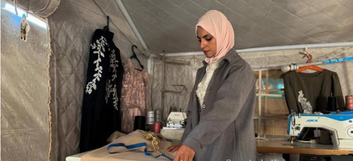 في خيمة النزوح ..  "إسراء" تعيد الحياة لماكينة الخياطة  